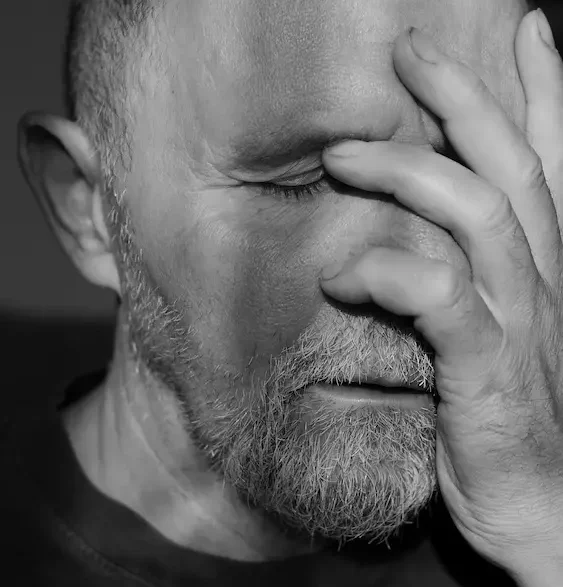 Distressed man resting his hand over his face, reflecting the stress of being served with an AVO